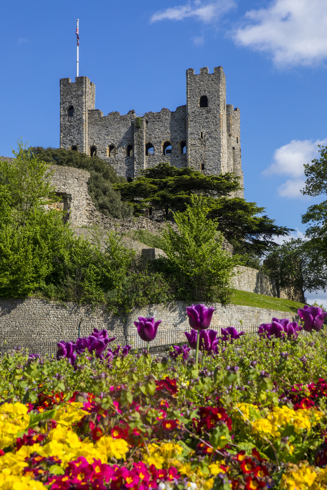 A view of Rochester Castle with beautiful flowers in the foreground, in the historic city of Rochester in Kent, UK. One of the castles near London. 