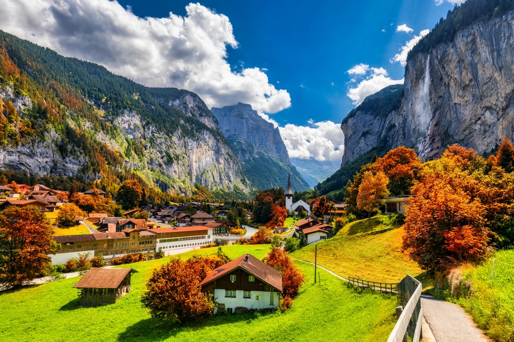 a town in a valley in the mountains, buildings can be seen spread out in the hills, fall foliage can be seen in the trees