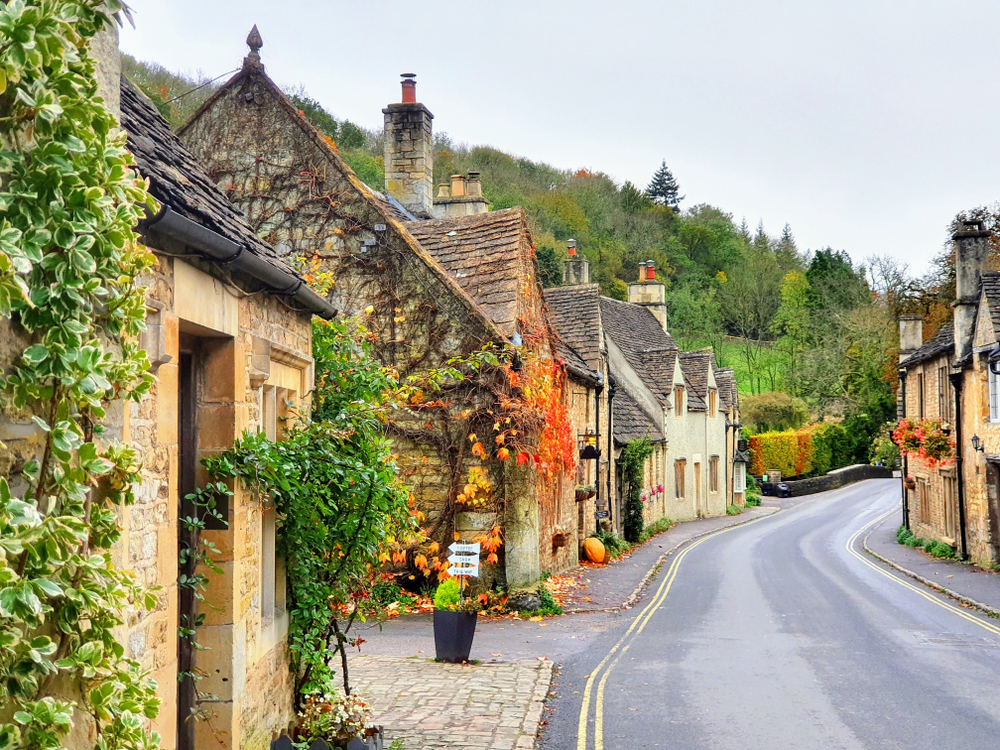 a road in England with ivy covered buildings on both sides on a gloomy day,best places to visit in Europe in October