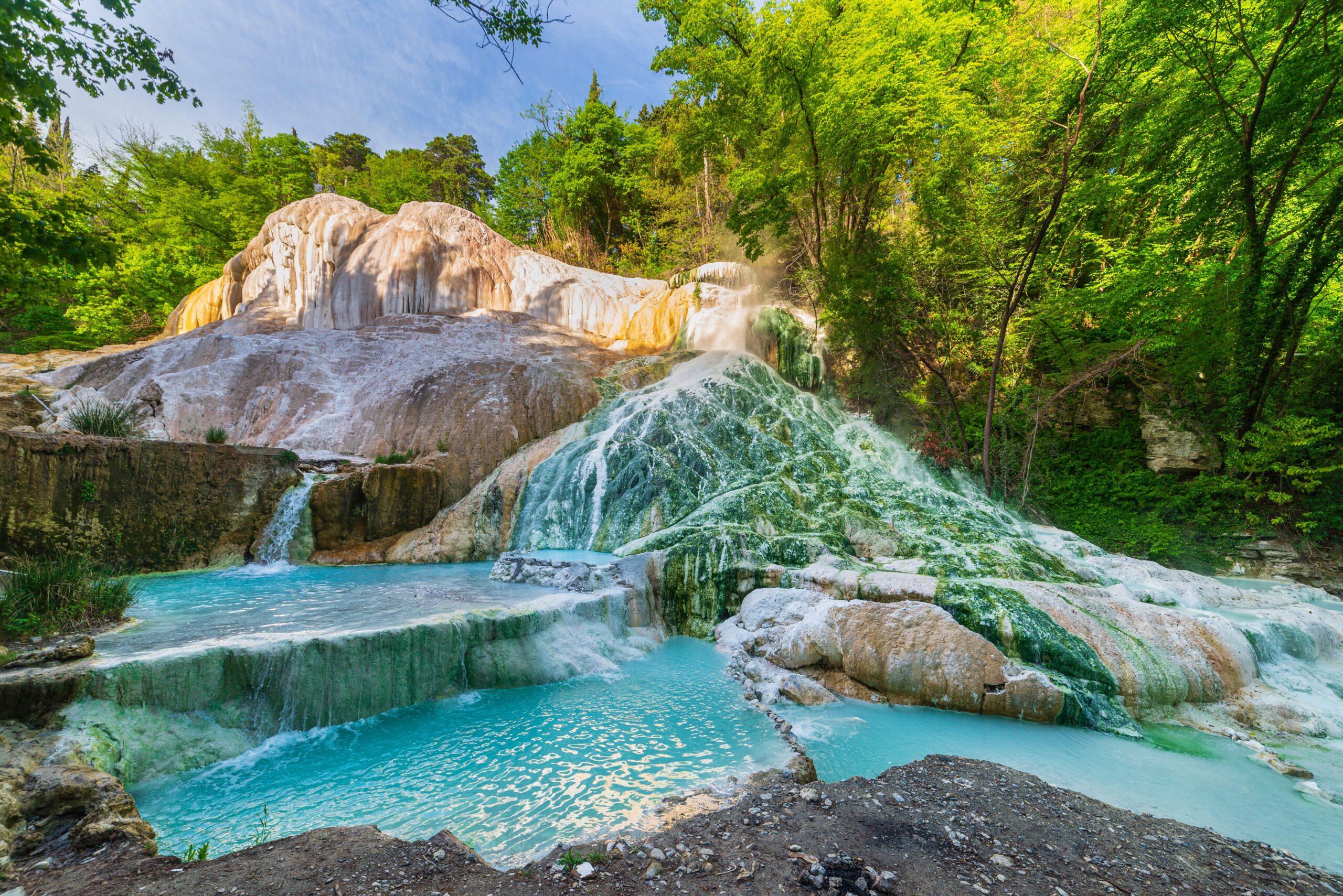 View of the unbelievably teal waters of a mineral rich waterfall at Bagni di San Filippo hot springs 