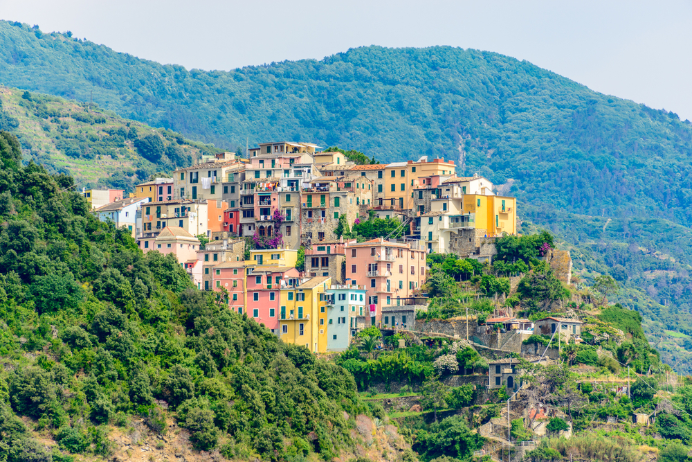 Corniglia in Cinque Terre, Italy, view at the town from mountain trail. You can see the town and the green mountains surrounding them. 