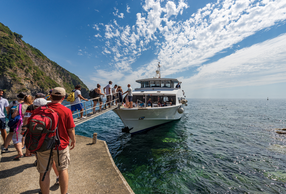  Ferry with tourists docked in front of the small village of Riomaggiore, Cinque Terre National Park