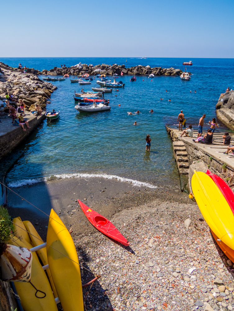  View of the port of Riomaggiore, Cinque Terre, Italy. UNESCO World Heritage Site. You can see kayaks and people swimming in the water. 