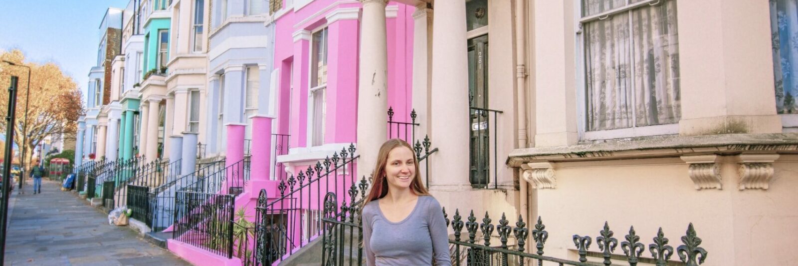 a girl in pink skirt standing in front of the colorful buildings in Notting Hill