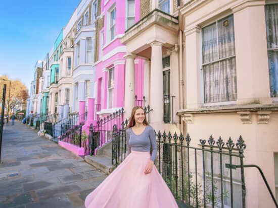 a girl in pink skirt standing in front of the colorful buildings in Notting Hill