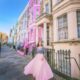 a girl in pink skirt standing in front of the colorful buildings in Notting Hill