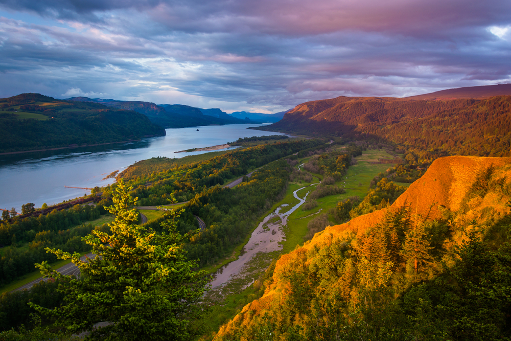 Sunset view looking down at the Columbia River Gorge with rolling hills and the river.