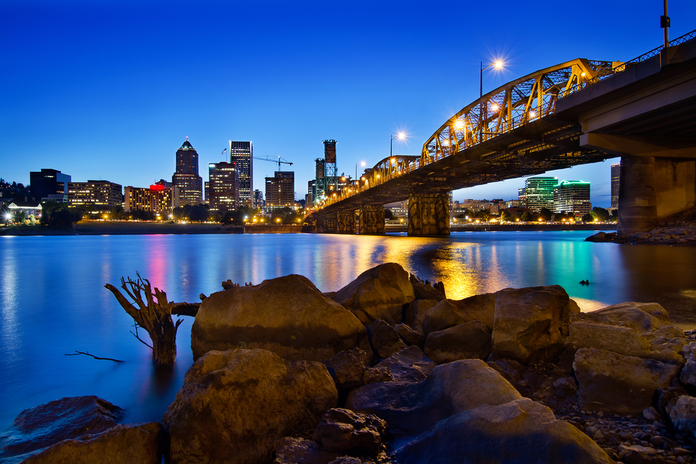 Dusk over the Portland skyline viewed from across the river with a lit up bridge during an Oregon road trip.