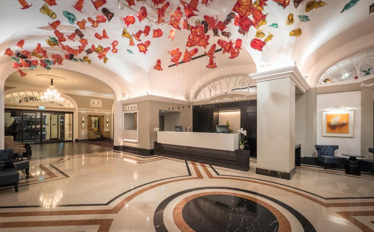 Stylish lobby at the Riu Plaza The Gresham Dublin hotel with a check in counter and colorful art installation hanging from the ceiling.