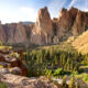 Sunny day over Smith Rock State Park with rugged rocks and a forest below.