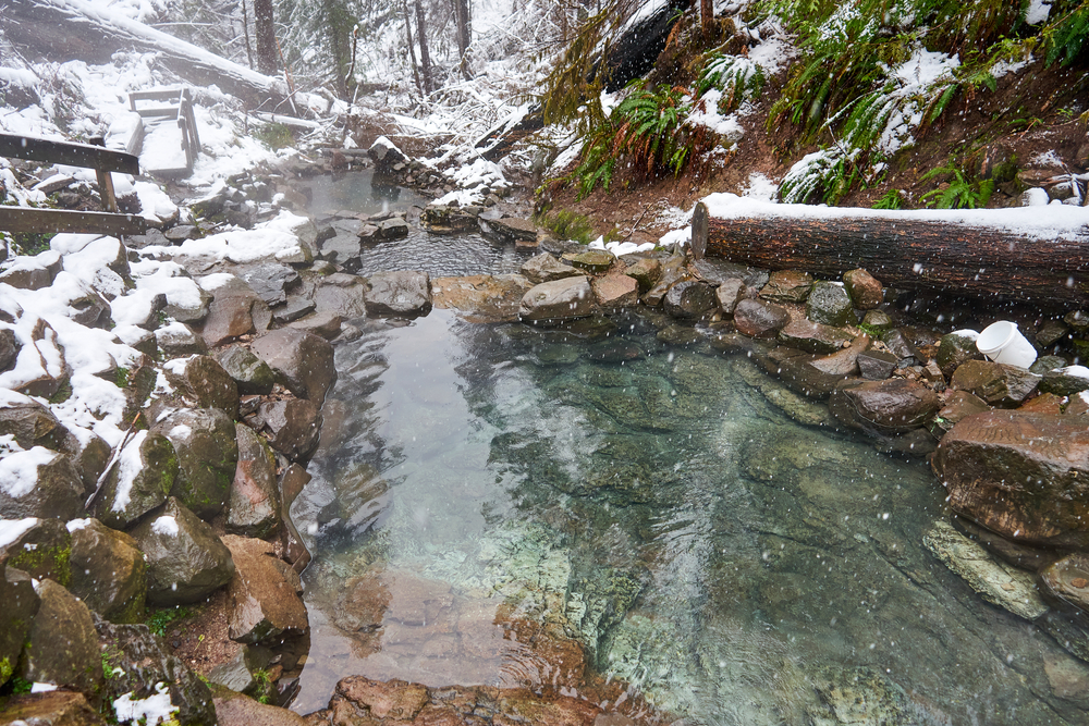Snowy day at the Terwilliger Hot Springs with multiple pools surrounded by stones.
