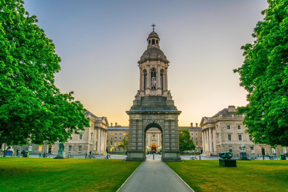 Purple dusk over Trinity College with historic arch and bell tower.