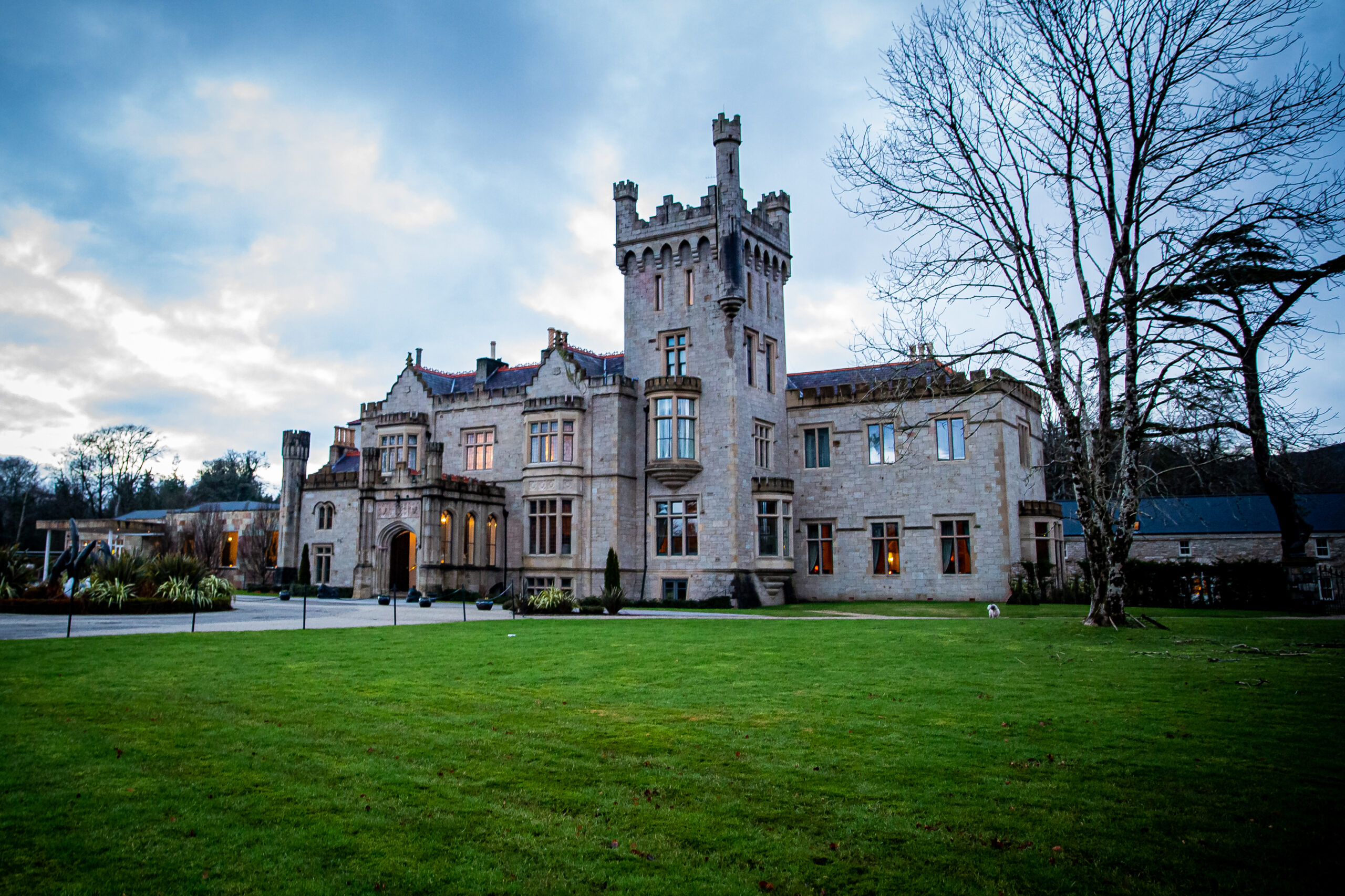 The grey stonework and epic turrets of Lough Eske Castle. This view shows that the castle has lots of beautiful bay windows. 