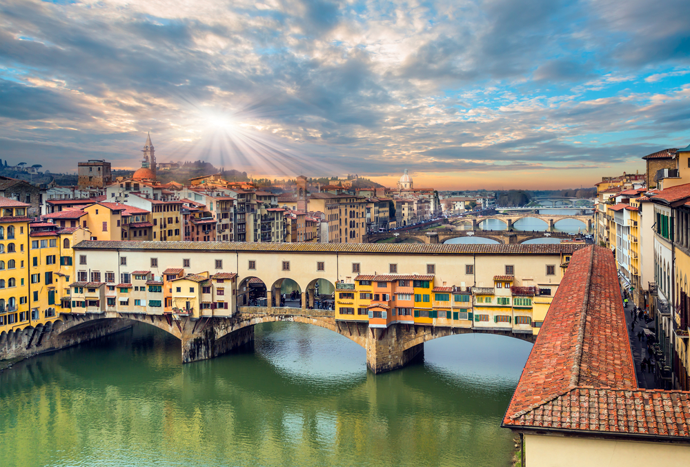 Ponte Vecchio over Arno river in Florence of the iconic bridge see historical Florence in the background at sunset