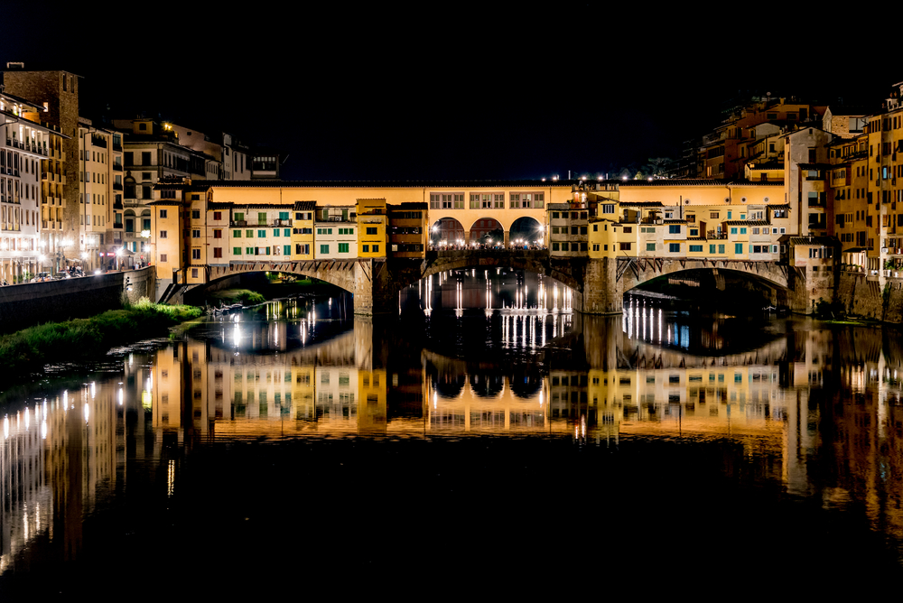 nighttime view of Arno river with bridge in background