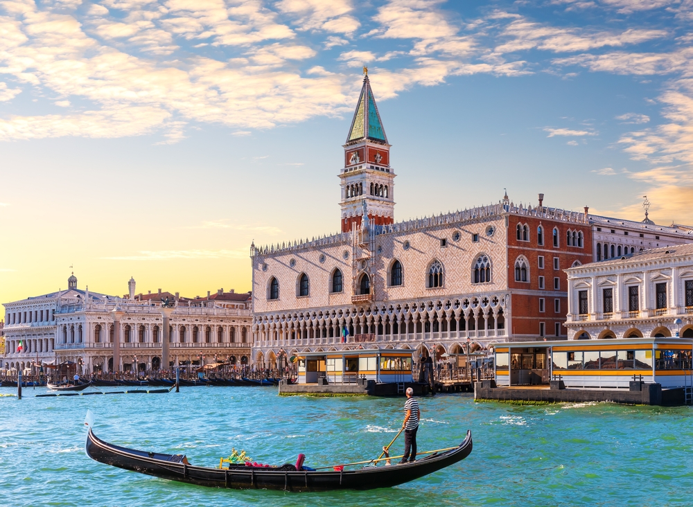 a view of the Doge Palace from the water with a gondola and boats in front 