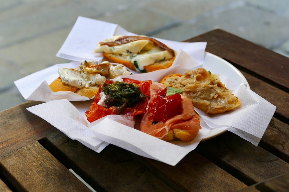 a plate of Venitian Cicchetti - with toasted bread topped with fish and cheese and roasted veggies