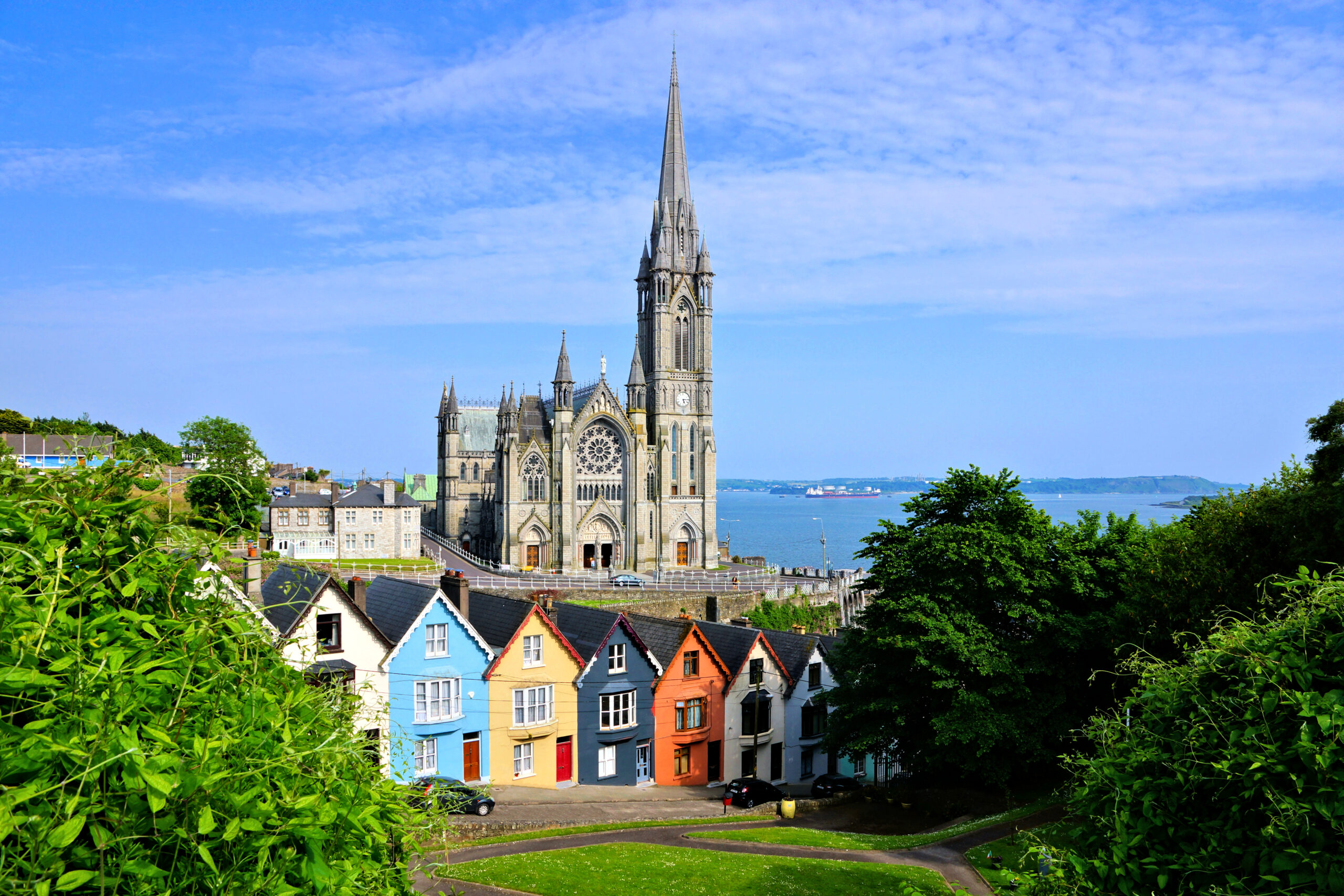 View of the famous colorful deck of cards houses with Cobh's cathedral in the background 