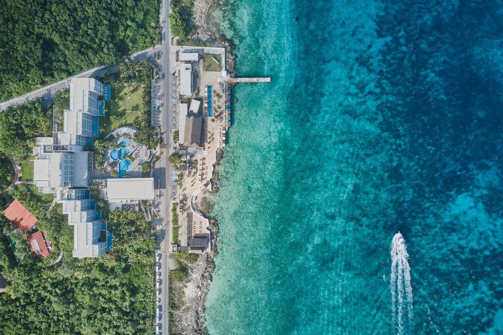 Picture taken from above of one of the best affordable all inclusive resorts. You are see the resort, the water and a boat on the water. 