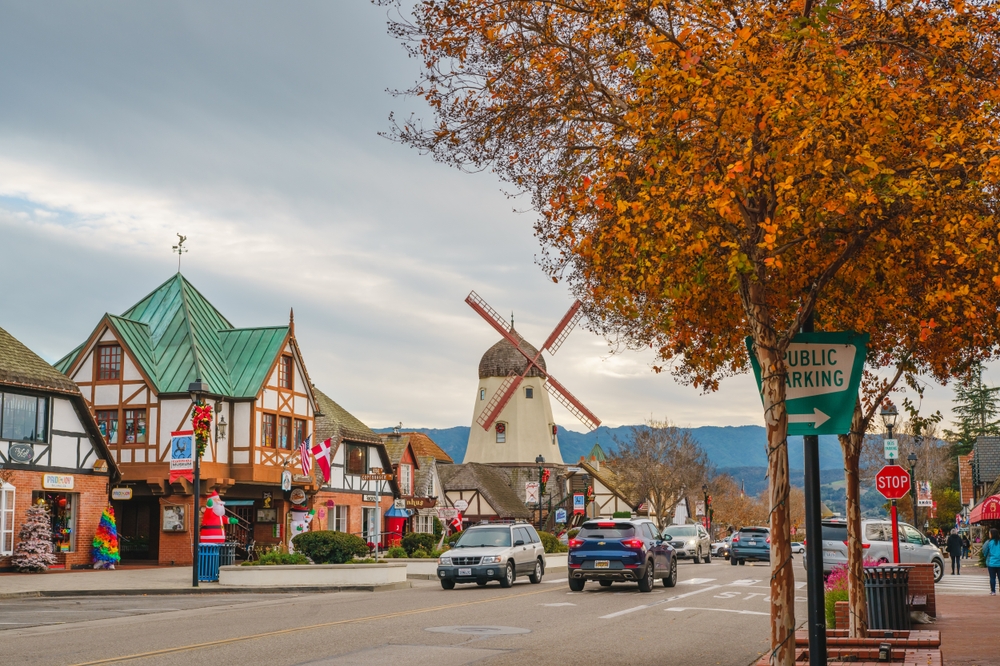 The town of Solvang with Danish architecture and a windmill on a cloudy day with fall foliage.