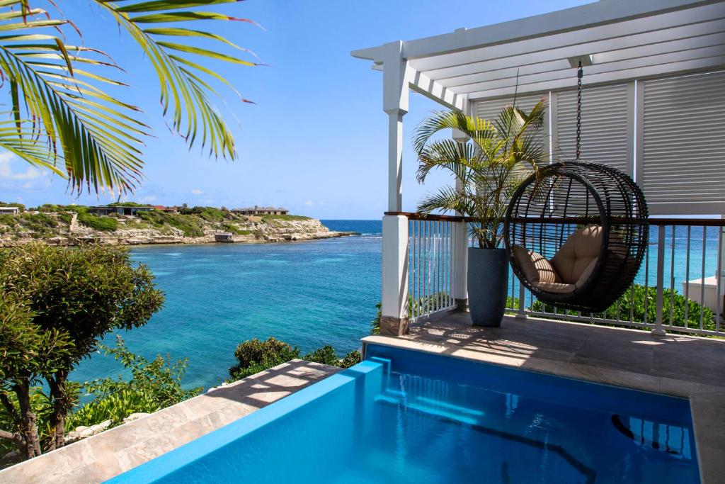 View from a hotel room on one of the best adults only all inclusive resorts. You can see a pool and a chair swing with the ocean in the distance. 