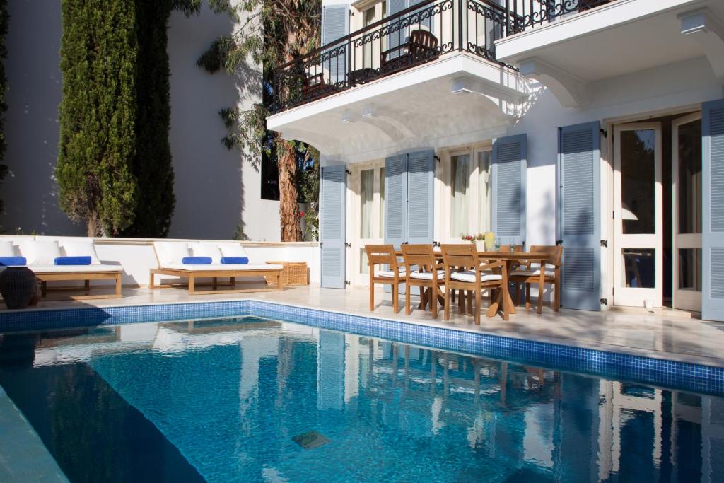 View of a private hotel pool surrounded by a dining table and chairs and loungers. 