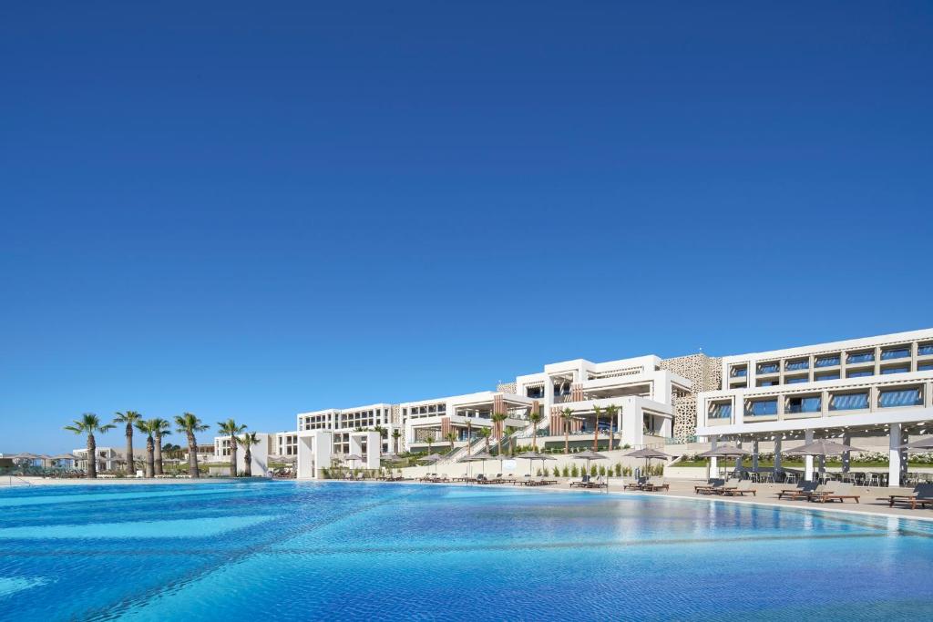 Huge hotel pool surrounded by white buildings and palm trees. 