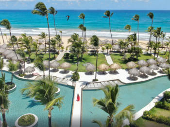 woman in red dress walking across pool with ocean in the background