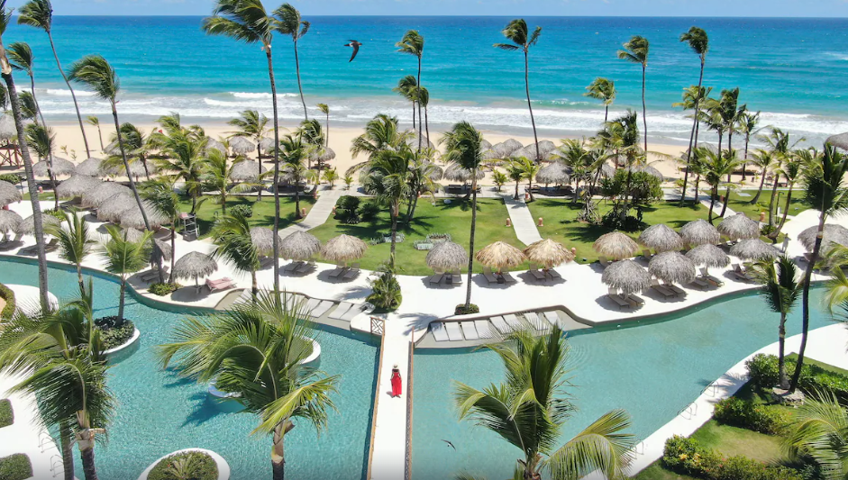 woman in red dress walking across pool with ocean in the background