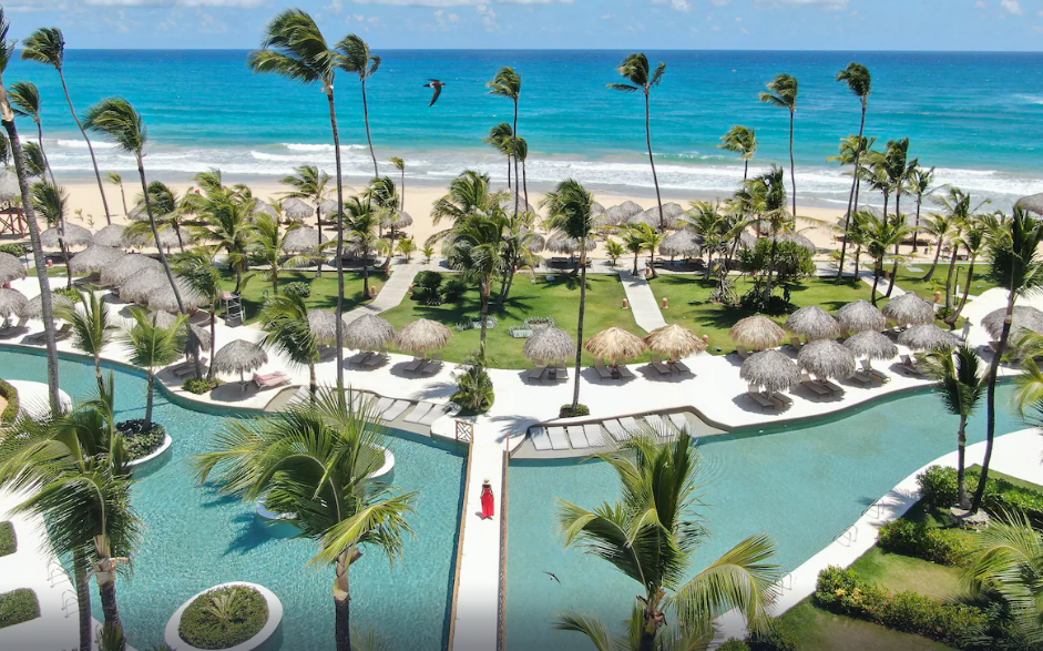 Taken from above a girl walking across a bridge over a swimming pool towards the ocean. 