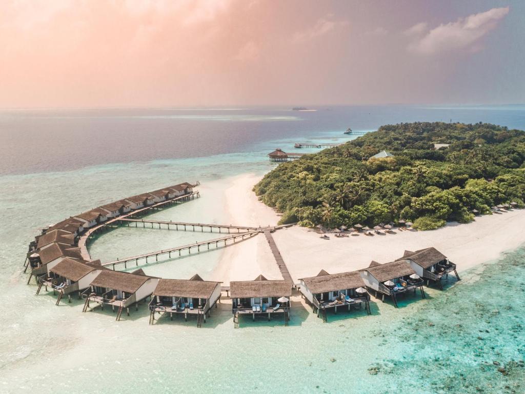 Picture of water bungalows with a walkways from a small green island. 