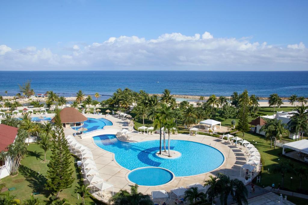 Hotel pool surrounded by green space and overlooking the ocean. 