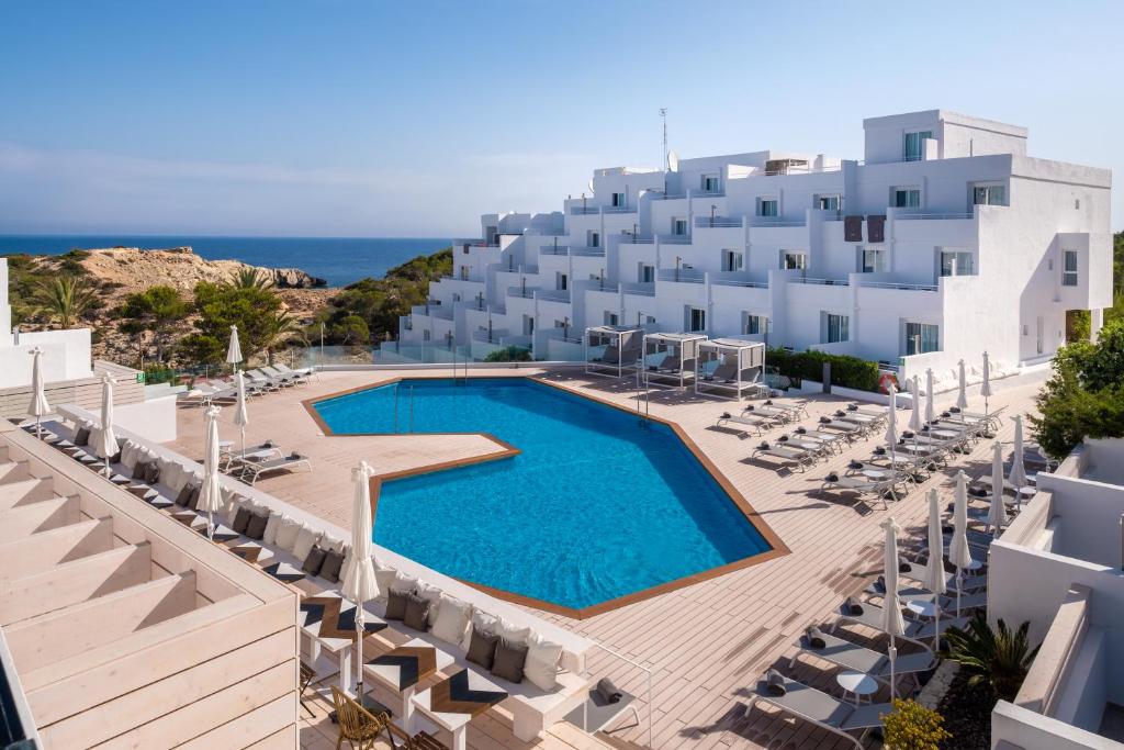 One of the best affordable all inclusive resorts in Spain. You can see the pool with a white building around it. You can see the sea in the background. 