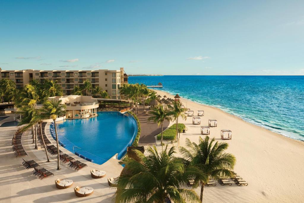 View of a pool and beach at one of the best affordable all inclusive resorts. You can see the sea and buildings. 