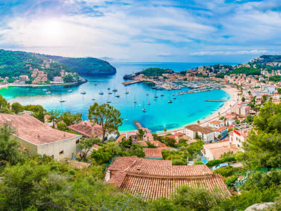 european beach town located along the blue water with houses with brown roofs and blue sky