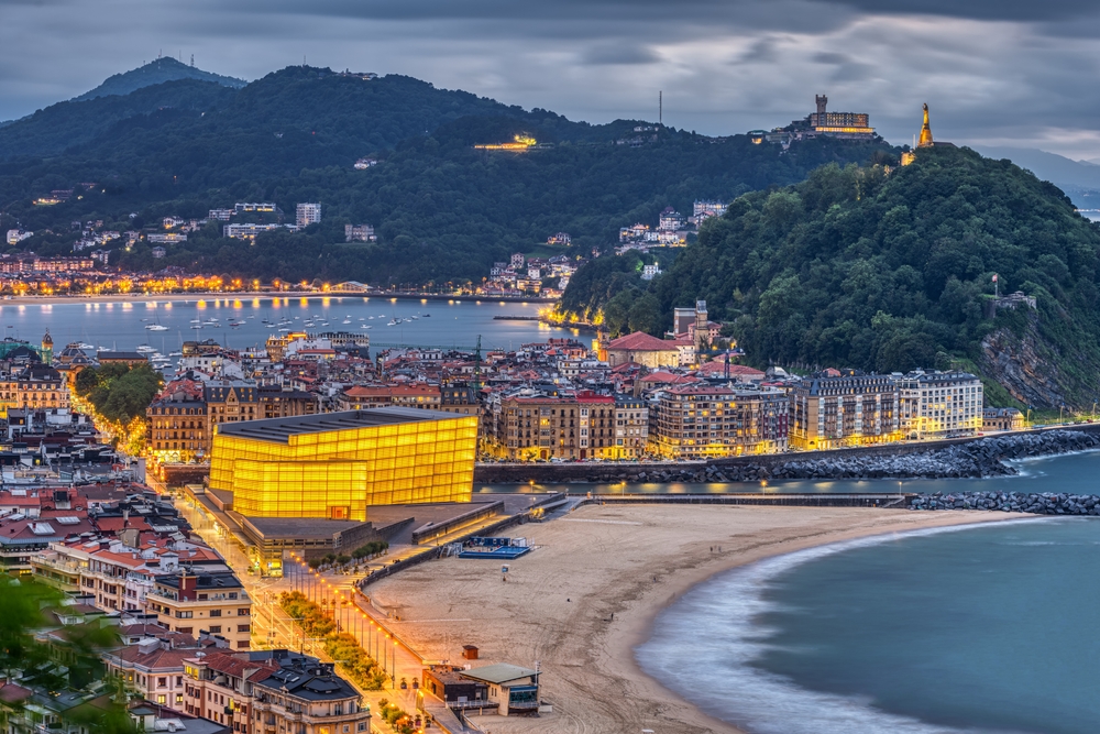San Sebastian in northern Spain with the iconic Kursaal at dusk. You can see the beach and mountains in the background. It is one of the best beach towns in Europe. 