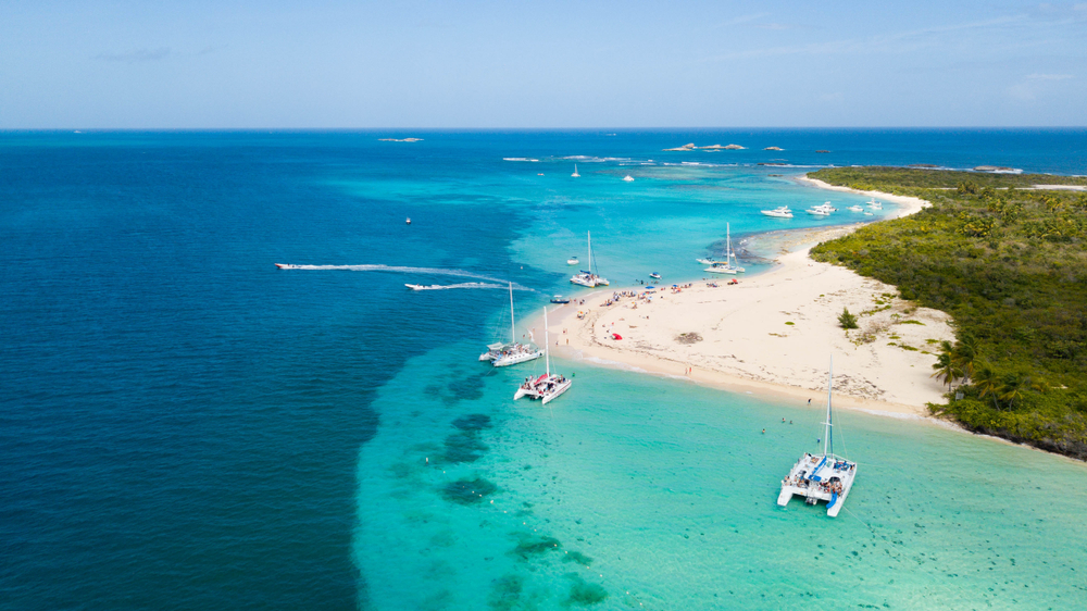 Aerial view of Cayo Icacos, Puerto Rico showing the coastline on the right, several boats anchored near the shore, and blue water stretching to the horizon. 