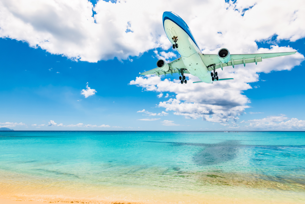 An airplane starting its descent over the water at Maho Beach, one of the best beaches in the Caribbean. 