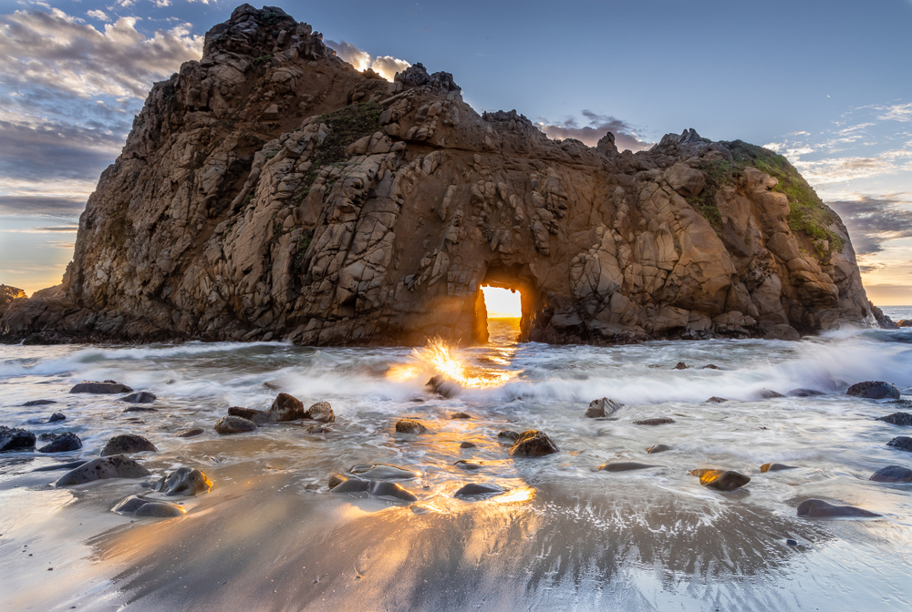 The Keyhole Arch at Pfieffer Beach, one of the best beaches in the USA.  At sunset, sunlight passes through the arch creating an orange glow. 