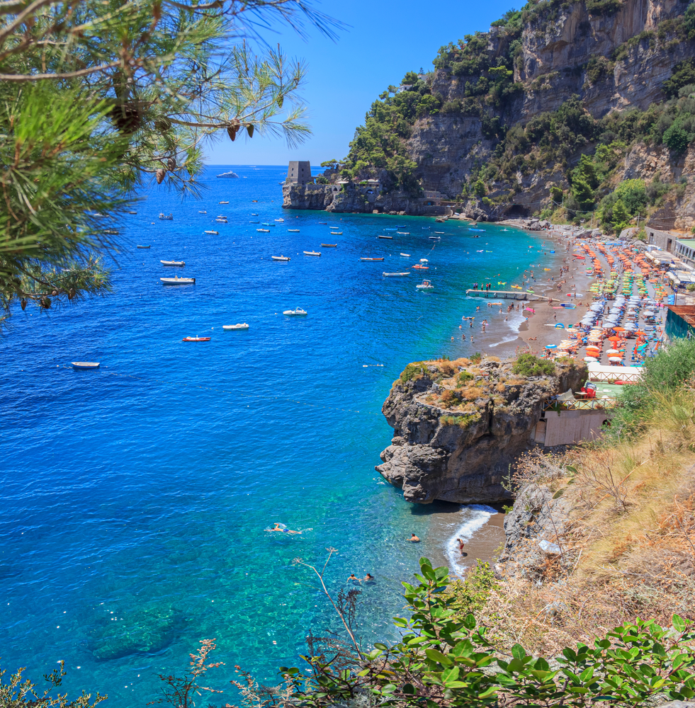 the hidden oasis beach wit boats in water surrounded by cliffs and umbrellas on th beach