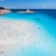 la pelosa beach in europe with clear blue water and people enjoying the beach. the sky is blue