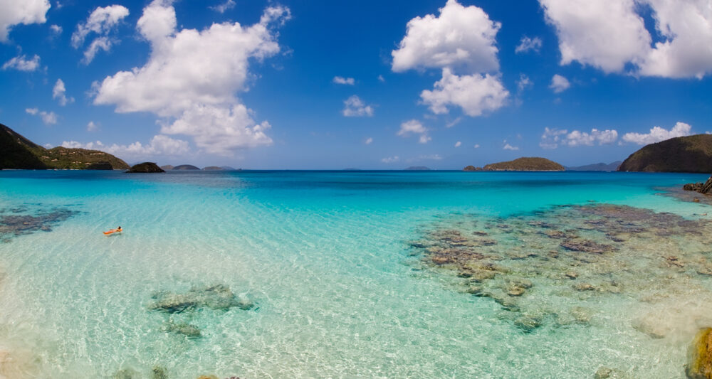 clear blue water of the USVI with rocks and clouds in a blue sky
