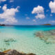 clear blue water of the USVI with rocks and clouds in a blue sky