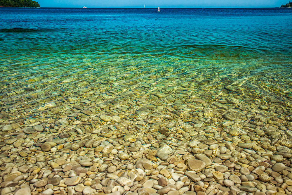 Smooth limestone rocks gather beneath the crystal clear water at Schoolhouse Beach in Wisconsin. 