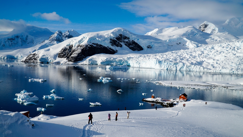 Cold arctic winter landscapes in Paradise Bay of Antarctica. You can see people on the ice and snow covered mountains in the background. 