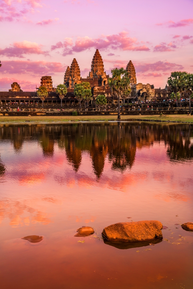 Sunrise view of popular tourist attraction ancient temple complex Angkor Wat with reflection in Siem Reap lake, Cambodia. One of the once in a lifetime travel destinations. 