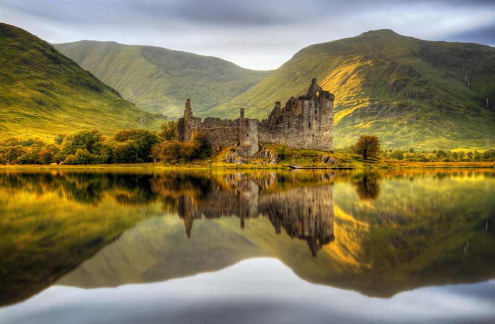 Kilchurn Castle reflections in Loch Awe at sunset, Scotland. You can see the mounatins in the background and the lake in the foreground. 