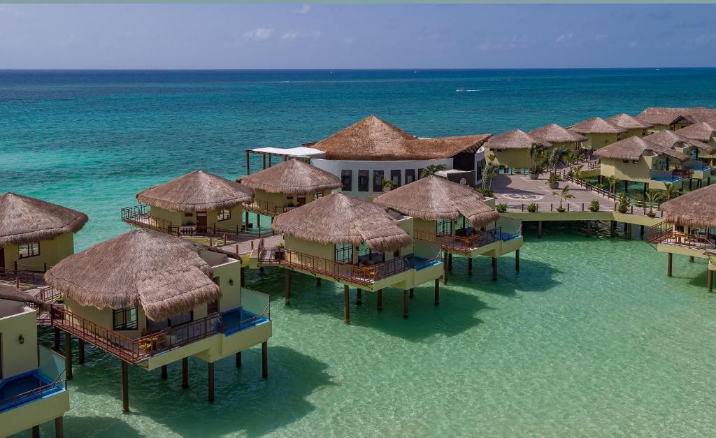 Overwater villas in a cluster. All have pools and a thatched roof. 