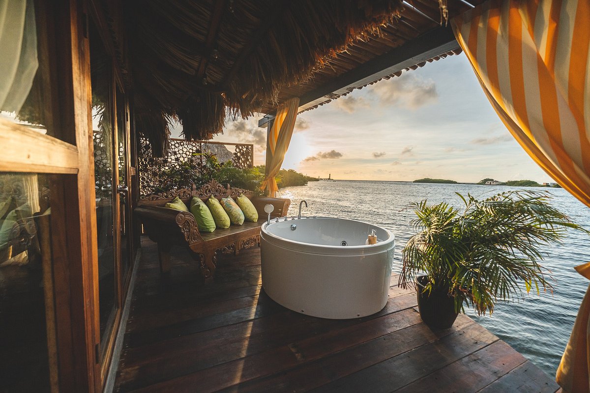 Deck showing a bath an settee over the water. The article is about overwater bungalows near Florida. 