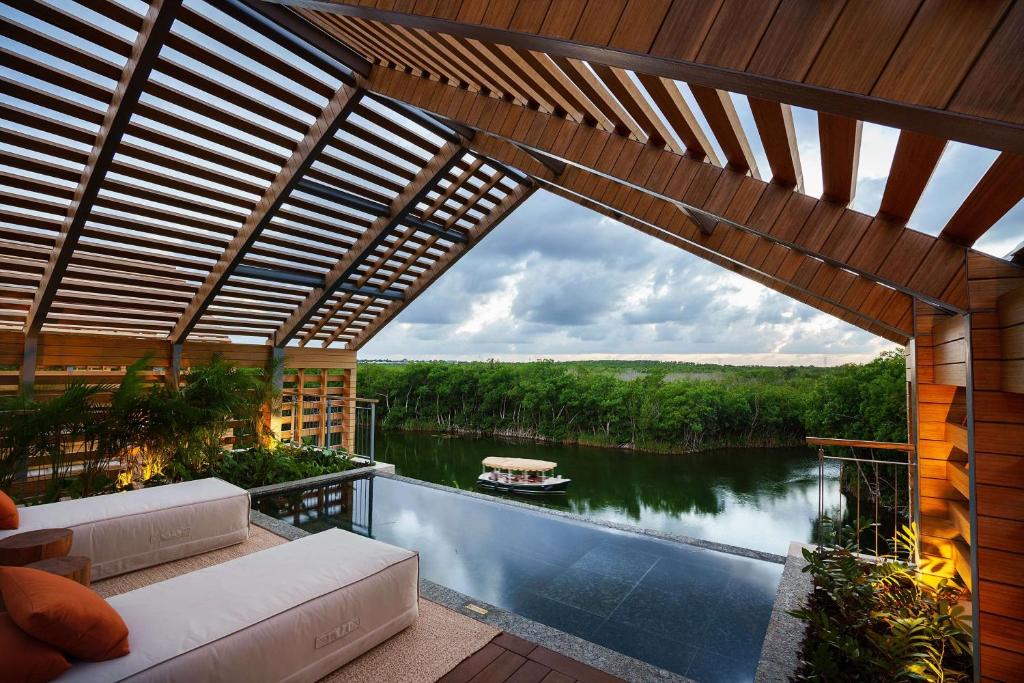 A rooftop of a villa. You can see a slated roof, lounge chairs, a plunge pool and the view of a lake. The lake has a boat on and there are trees in the background. 